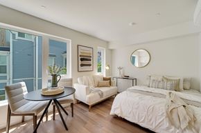 Berkeley apartment for rent - A bedroom with a white bed and a round mirror on the wall.