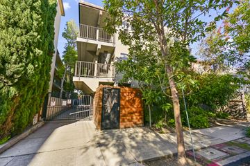 Berkeley apartment for rent - A tree stands in front of a building with a gate.