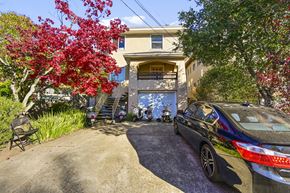 Berkeley apartment for rent - A car is parked in front of a house with a tree with red leaves.