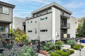 Berkeley apartment for rent - A grey building with a balcony and a small garden in front.