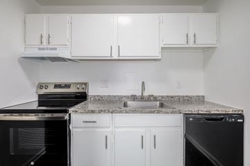 Waldorf apartment for rent - A kitchen with white cabinets and black appliances.