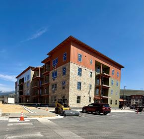 Missoula apartment for rent - A large multi-story building with a red roof and a parking lot in front.