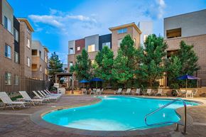 Englewood apartment for rent - a swimming pool with chairs and umbrellas in front of an apartment building