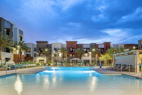 Chandler apartment for rent - a swimming pool with palm trees and apartments in the background