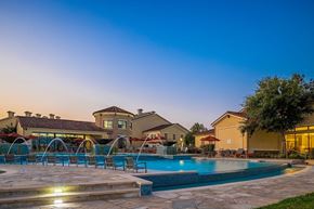Katy apartment for rent - A pool surrounded by a stone patio and a house in the background.