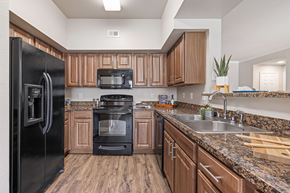 Houston apartment for rent - A kitchen with a black refrigerator and wooden cabinets.