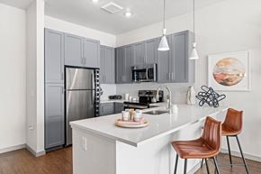 Aurora apartment for rent - A kitchen with a white counter top and brown chairs.