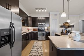 Katy apartment for rent - A modern kitchen with a refrigerator on the left and a clock on the wall.