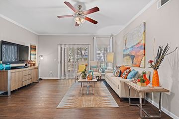 Austin apartment for rent - A living room with a white ceiling fan and a white couch with orange pillows.