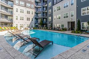 Atlanta apartment for rent - A swimming pool surrounded by lounge chairs and buildings.