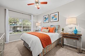 Austin apartment for rent - A bedroom with a bed, a table with a lamp, and a ceiling fan.