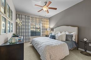 Katy apartment for rent - A bedroom with a bed, nightstand, and a ceiling fan.