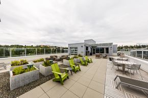 Seattle apartment for rent - A rooftop patio with green chairs and a building in the background.