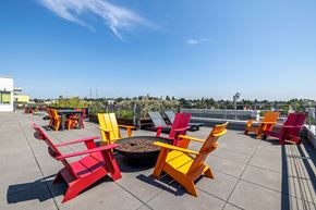 Seattle apartment for rent - a patio with colorful chairs and a fire pit on top of a building