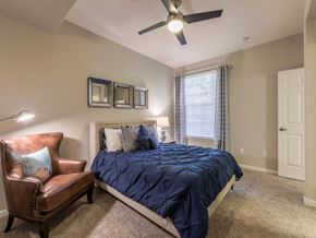 Castle Pines apartment for rent - A bedroom with a bed, chair, and ceiling fan.