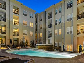 Lone Tree apartment for rent - A swimming pool is surrounded by a patio area with chairs and umbrellas at the base of apartment buildings.