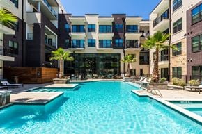 Houston apartment for rent - a swimming pool in front of an apartment building with palm trees