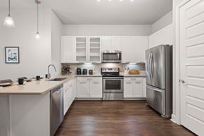 Houston apartment for rent - A modern kitchen with white cabinets and stainless steel appliances.