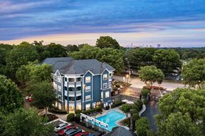 Atlanta apartment for rent - A large apartment complex with a pool and cars parked in the driveway.