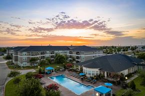 Rockwall apartment for rent - A sunset view of a resort with a pool and multiple buildings.