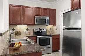 Rockwall apartment for rent - A kitchen with brown cabinets and a stainless steel refrigerator.