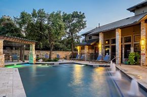 Austin apartment for rent - A pool with a waterfall in front of a house.