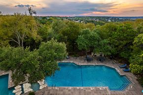 Austin apartment for rent - an aerial view of a pool with trees and a sunset