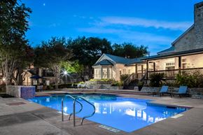 San Antonio apartment for rent - a swimming pool with lounge chairs and umbrellas in front of a brick building