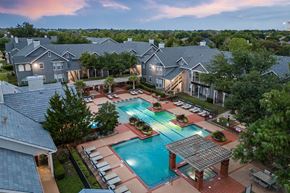 Flower Mound apartment for rent - A swimming pool surrounded by a brick patio and lounge chairs.