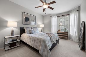 Flower Mound apartment for rent - A bedroom with a large bed and a ceiling fan.