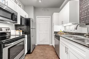 Dallas apartment for rent - A kitchen with white cabinets and black appliances.