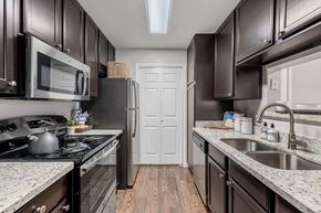 Houston apartment for rent - A kitchen with dark brown cabinets and a white door in the background.