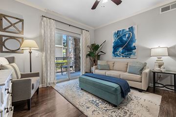 Houston apartment for rent - A living room with a blue couch and a painting on the wall.