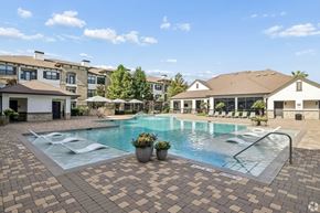 Katy apartment for rent - A swimming pool surrounded by a brick patio and buildings in the background.