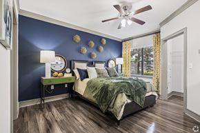 Katy apartment for rent - A bedroom with a bed, a table with a lamp, and a ceiling fan.