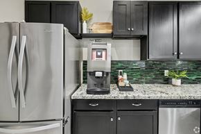 Katy apartment for rent - A modern kitchen with a stainless steel refrigerator and black cabinets.