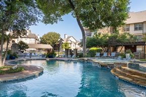 Fort Worth apartment for rent - A large swimming pool surrounded by trees and lounge chairs.
