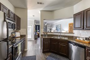 Fort Worth apartment for rent - A kitchen with dark wood cabinets and a stainless steel dishwasher.