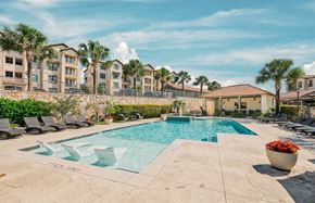 San Antonio apartment for rent - A large swimming pool surrounded by lounge chairs and palm trees.