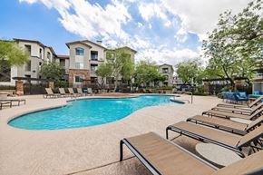 Phoenix apartment for rent - A swimming pool surrounded by lounge chairs and apartment buildings.