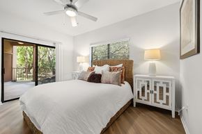 Austin apartment for rent - A bedroom with a large bed, a ceiling fan, and a sliding glass door.