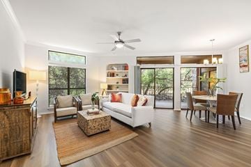 Austin apartment for rent - A living room with a white couch, a wooden floor, and a ceiling fan.