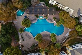 Austin apartment for rent - An aerial view of a swimming pool surrounded by trees and buildings.