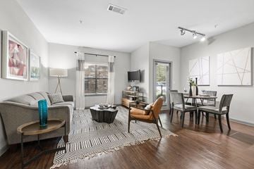 Katy apartment for rent - A living room with a grey couch, a coffee table, a dining table with chairs, and a television.