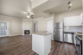 Broomfield apartment for rent - A kitchen with a stainless steel refrigerator and oven, and a fireplace in the living room.