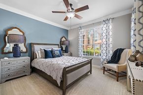 Houston apartment for rent - A bedroom with a bed, chair, and a ceiling fan.