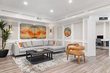Houston apartment for rent - A living room with a grey sofa, a wooden chair, and a painting on the wall.