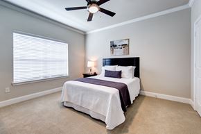Houston apartment for rent - A bedroom with a bed, a ceiling fan, and a window with blinds.