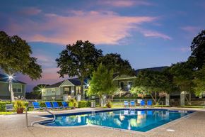 Flower Mound apartment for rent - a swimming pool with blue chairs around it at night