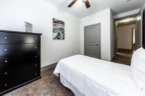 Austin apartment for rent - A bedroom with a white bed and a black dresser.